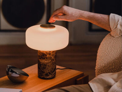Fonte table lamp with marble base and frosted glass shade emitting warm ambient light on a wooden side table.